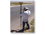 land surveyor standing on the side of the road taking measurements