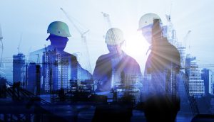 silhouettes of three men superimposed over a construction site, a blue hue covers them all as the sun shines brightly through the middle