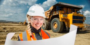 young woman wearing a hardhat and safety goggles smiling and holding a blueprint