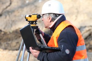 older land surveyor using a theodolite to survey land