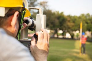 a land surveyor surveying the land of a park with a theodolite 