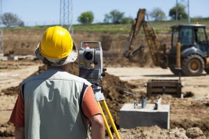 construction worker at a site with a theodolite