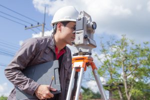 a land surveyor using a  theodolite to survey land