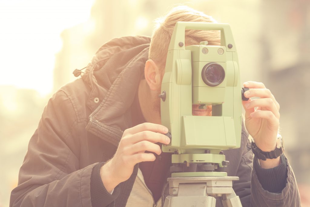 Man surveying land through land measuring equipment