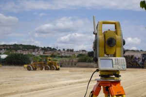 Land surveyor equipment with a developed plot in the background