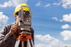 Land surveyor using equipment with blue sky in background