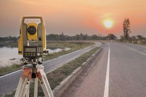 engineering survey equipment by a road at sunset