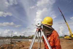 land surveyor worker working with equipment at factory construction site outdoors blue sky background