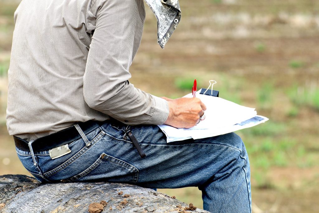 land surveyor taking notes while sitting on a rock