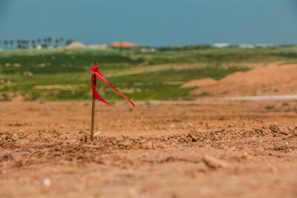 Metal survey peg with red flag on construction site.