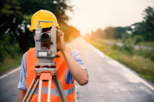 Survey by theodolite concept. Civil Engineer Checking Surveyor Equipment Tacheometer or theodolite outdoors at construction site on the road.